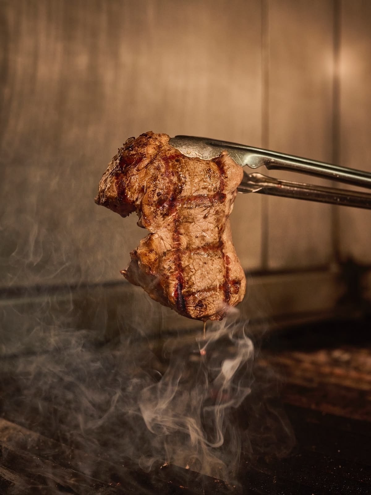 A grilled steak resting in the smoke